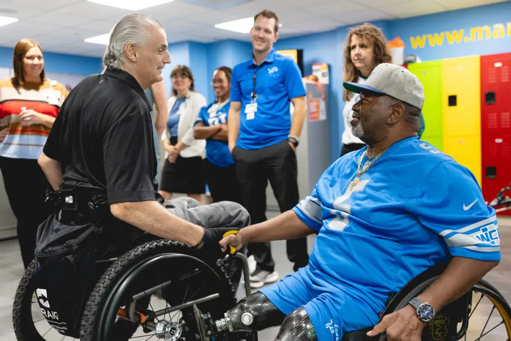 Mike Utley shown shaking hands with another wheelchair and adaptive sports athlete