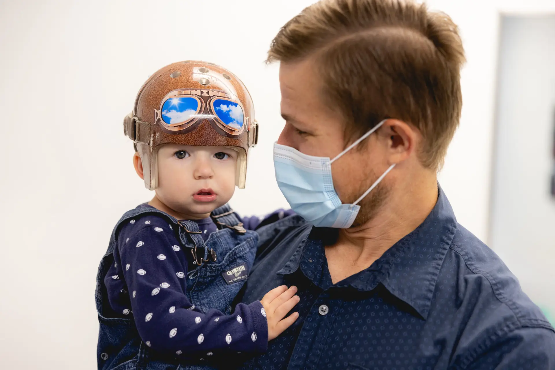 A parent holding their child who's wearing a custom cranial remolding helmet.