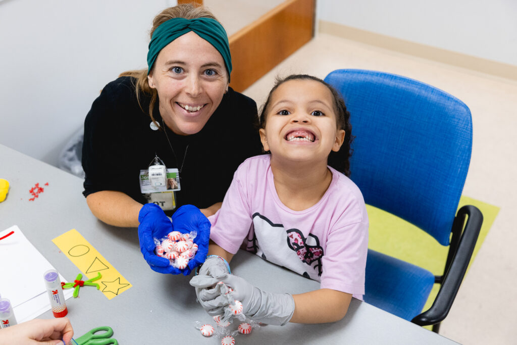 Art and music therapist working with a young child at a table, creating therapeutic art projects with colorful materials to support creative expression and healing"
